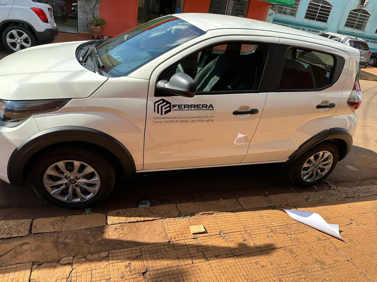 Veículos estacionados em uma rua da cidade, representando um veículo da frota corporativa para serviços de limpeza industrial.