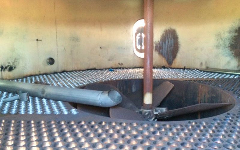 Interior de um vaso de pressão ou tanque sujo, com uma estrutura em forma de hélice e piso perfurado.