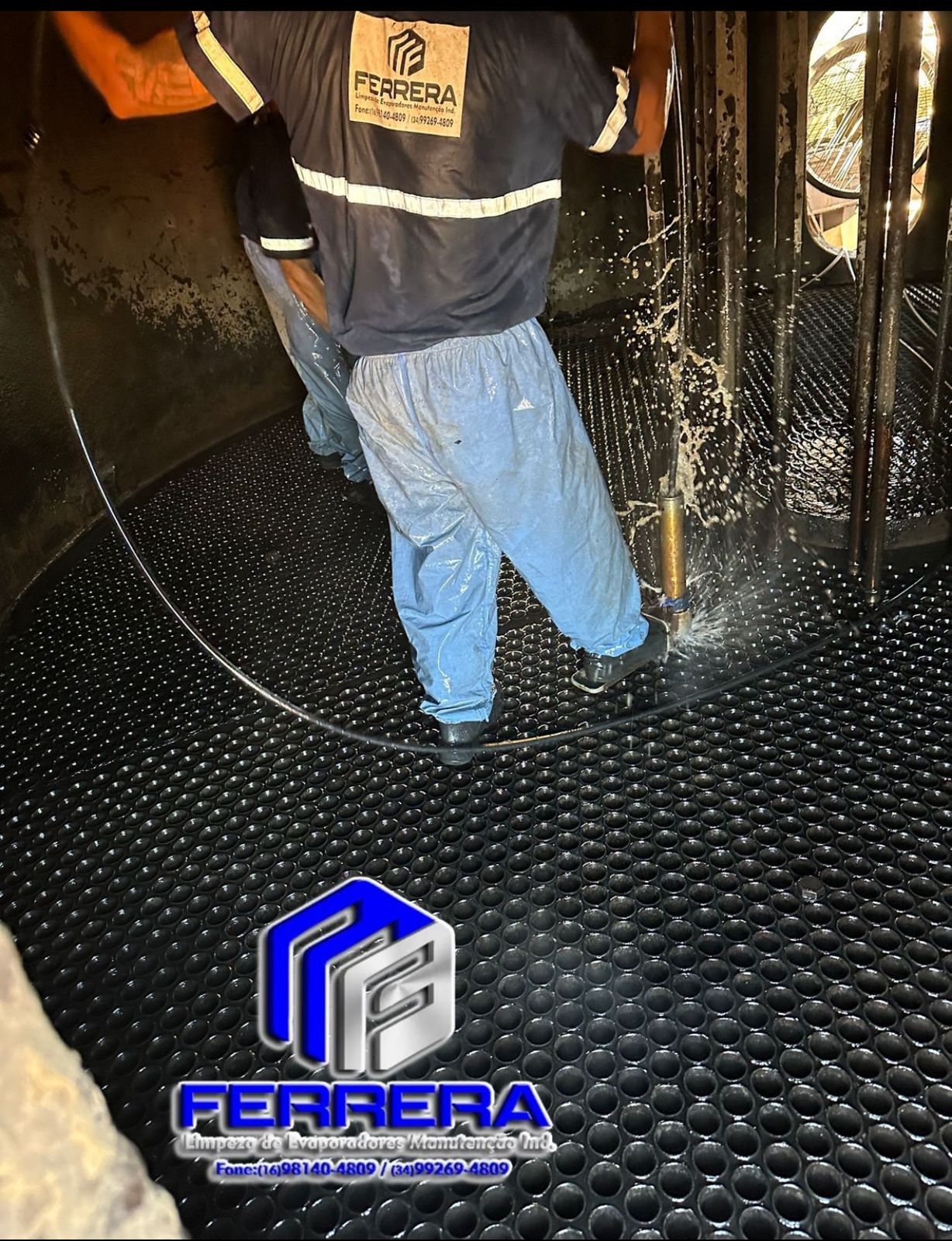 Técnicos de limpeza industrial usando jatos de água para higienizar o piso e a parede interna de um tanque.