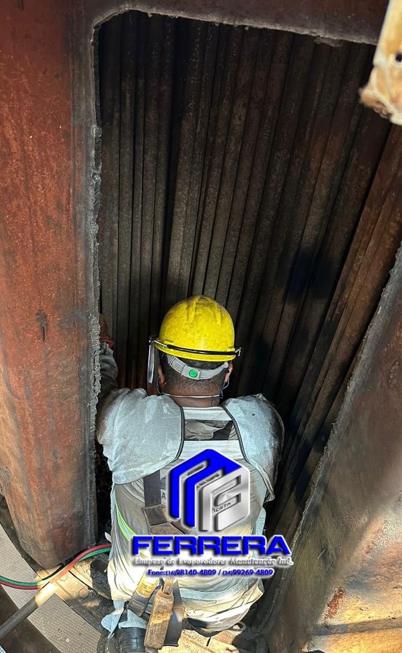 Profissional usando EPI, trabalhando na manutenção de um trocador de calor industrial.